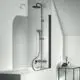 Duschsystem von Ideal Standard mit eleganter, schwarzer Armatur und klarer Glasduschabtrennung, installiert über einer Badewanne in einem minimalistischen Raum.